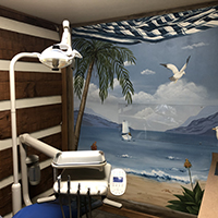 A dental chair and equipment looking at a wall painted to look like the beach at Cedar Lane Family Dentistry in Franklin, IN.