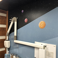 Dental machine resting against a wall painted to look like the solar system at Cedar Lane Family Dentistry in Franklin, IN.